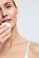 Woman skincare closeup, cotton pad on face, gentle beauty care routine, spa hygiene, moisturized skin texture, soft light, calm expression, minimal background