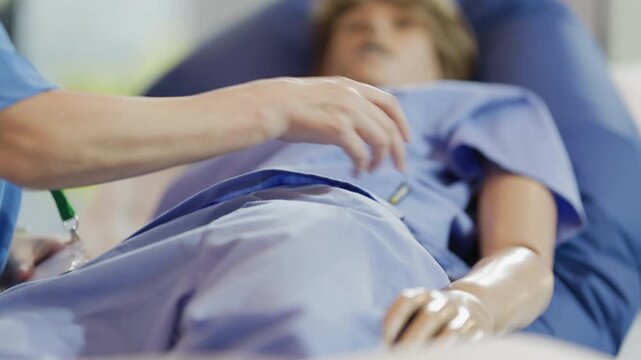 Nurse performing palpation exam on mannequin patient for medical training