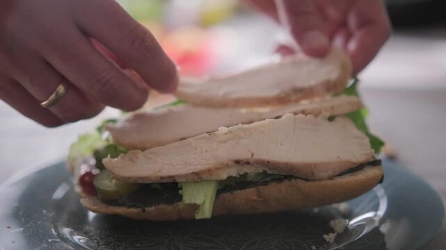Close up hands placing chicken on sandwich, home cooking process, healthy eating concept, suitable for food blogs, advertising, cafe menus and lifestyle content