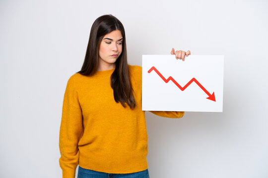 Young Brazilian woman isolated on white background holding a sign with a decreasing statistics arrow symbol with sad expression