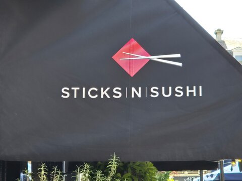 London UK 04.07.2025 Sticks n Sushi restaurant branding on black outdoor canopy with minimalistic logo and chopsticks symbol representing modern japanese dining concept