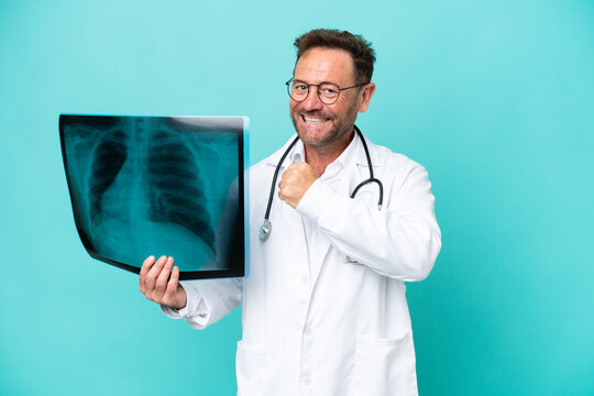 Middle age professional traumatologist doctor man isolated on blue background celebrating a victory