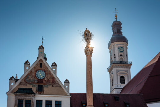 Two white storks are building a nest on the historic Marian column in the old town of Freising