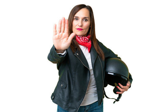 Middle age caucasian woman with a motorcycle helmet over isolated chroma key background making stop gesture