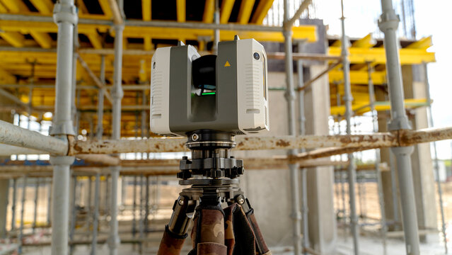Surveying laser mounted on tripod amid construction scaffolding