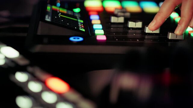 audio producer hand adjusting faders mixing console sound studio. Music engineer controlling levels colorful backlit buttons digital workstation. Close up finger sliding potentiometer creative