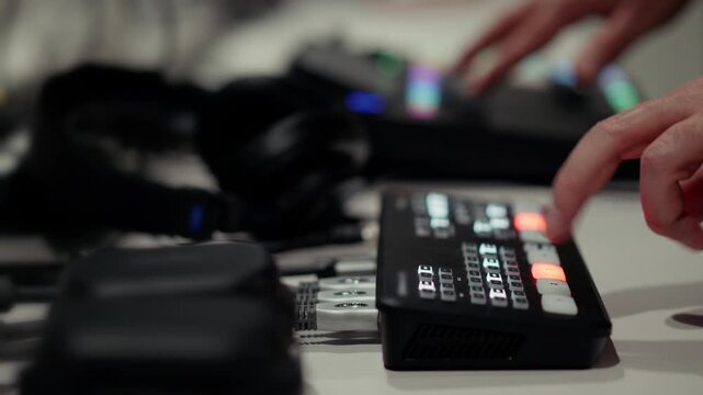 video switcher operator finger glowing button live podcast production. Technical director controlling multi camera broadcast digital streaming studio hardware. Close up hand switching