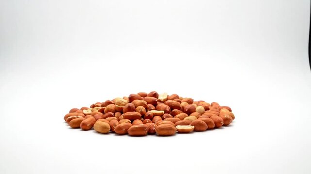 Close-up shot of a pile of raw, shelled peanuts against a plain white background, studio still life
