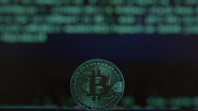 Close-up: physical Bitcoin coin, with a blurred green digital rain code falling. Golden BTC logo. Cryptocurrency, blockchain and cyberpunk concept. Borderless payments, instant global transfers