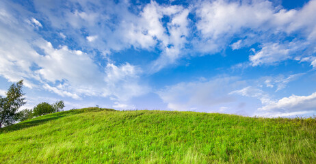 Obraz premium Vibrant green hill rises beneath wide blue sky