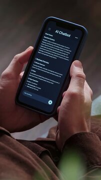 Close up of a man holding a smartphone, using an AI chatbot app for work, brainstorm a business project. Personal Artificial intelligence assistant helping with productivity. Vertical video