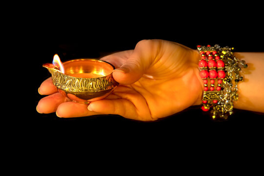 Hand with Diwali lamp diya or Deepavali or Deepawali. Hindu festival of lights. Celebrating in Indian religions Jainism and Sikhism. Offering to the gods, a spiritual rite. Close up view, out of focus