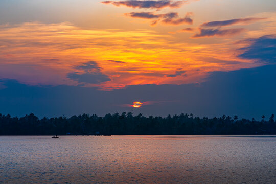 Golden Sunset Over the Serene Backwaters and Coconut Palm Silhouettes of Kuttanad, Kerala, India