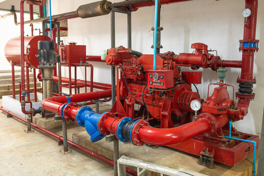 Red centrifugal fire pump with diesel drive and pressure gauges connected to expansion tank and blue vibration compensators