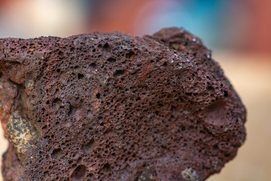 Macrophotographie d'une roche volcanique rouge poreuse (scorie).