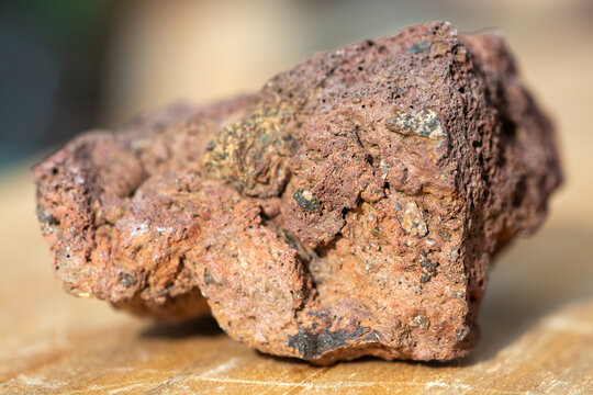 Macrophotographie d'une roche volcanique rouge poreuse (scorie).