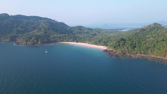Koh Muk, Thailand: Aerial drone footage of a sailboat anchored by the Farang or Charlie beach in the Koh Muk in the Andaman sea in Trang province in southern Thailand. Shot with a tilt up motion.