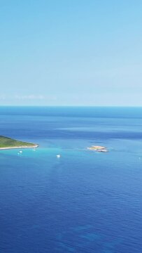 Scenic aerial view of the turquoise waters and coastline at Plage de Tamarone, with boats anchored near the shore under a clear blue sky.