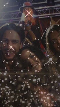 Vertical video: Singer starting gig singing on stage into mic trio posing for cam, bokeh over crowd