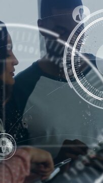 Vertical video: Woman in plaid shirt tapping tablet, initiating HUD overlay and team reviewing tech