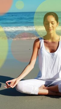 Vertical video: Yogi on sand starting prayer, doing mudras for wellness, circles over her