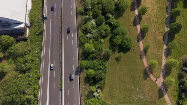Aerial View of Highway and Park: An aerial perspective showcases a bustling highway with cars moving alongside a serene park with winding paths and lush green trees.