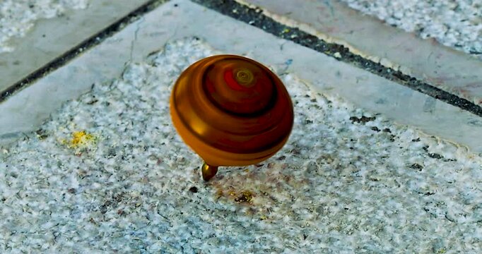 Trottola in  legno con punta in metallo tipica del Gargano ( Foggia , Puglia, Italia)in movimento su pavimento in pietra 