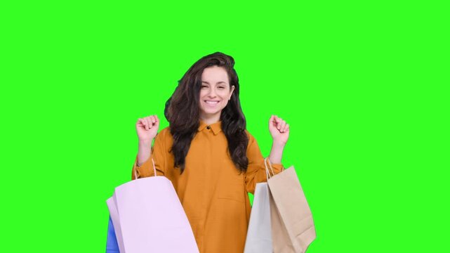 Happy young woman holding shopping bags while dancing on the chroma key