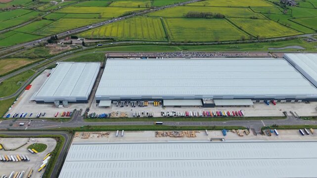 Drone shot of busy distribution warehouse with lorries loading at bays in the English Midlands
