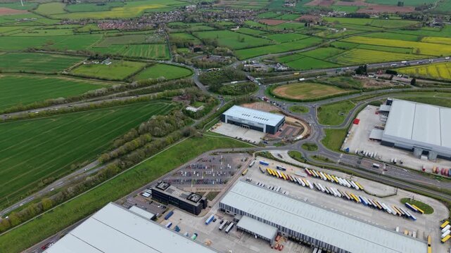 Aerial view of massive industrial warehouses and distribution hubs, showcasing the expansion of green-built logistics infrastructure into the rural Leicestershire countryside.