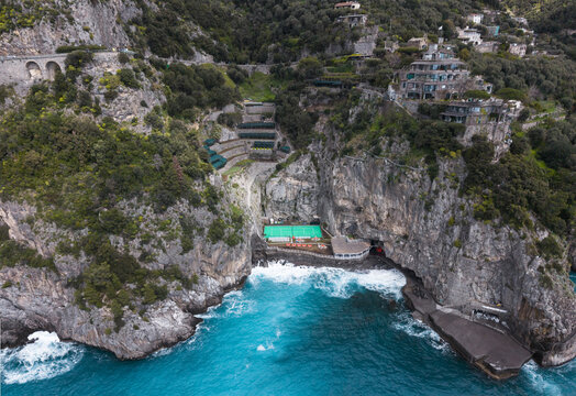 Aerial view of rugged cliffs meet the turquoise sea, revealing hidden pools and terraces cascading down the steep slopes, Laurito, Campania, Italy.