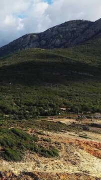 Scenic view of rugged mountains and lush greenery in the Delta du Fango region of Corsica, France, under a partly cloudy sky.