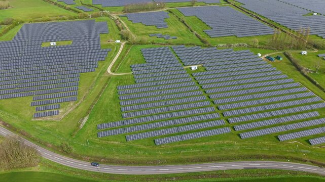 Wide drone shot of renewable energy solar panels integrated into British farmland, sunny photovoltaic energy generation UK 4k