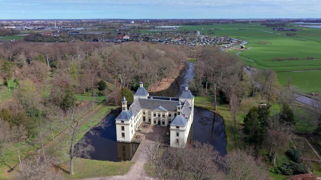 Aerial view of a historic castle surrounded by a moat and forest, captured by drone in rural landscape. Scenic architecture, symmetry, and natural environment in soft seasonal light.