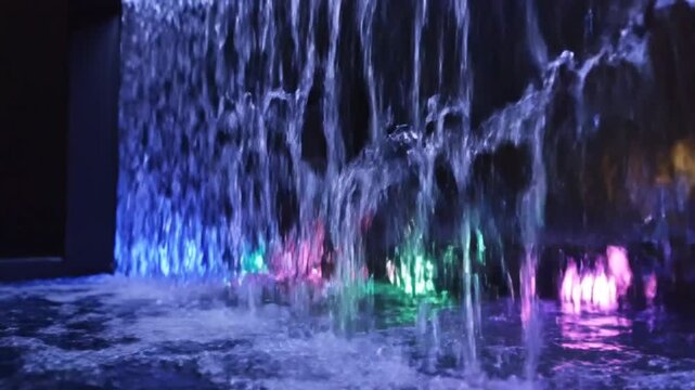 Tranquil indoor water feature with colorful illuminated cascading water creating a relaxing and calming ambiance