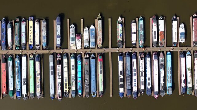 Aerial drone view of river barges and narrowboats moored in rows at Barton Marina, showcasing traditional canal culture and leisure travel near Burton on Trent, UK.