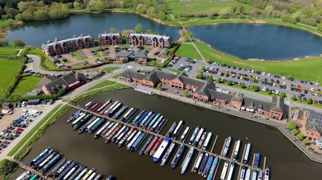 Aerial drone view of colorful narrowboats moored in symmetrical rows at Barton Marina, scenic canal boat harbor near Burton On Trent, UK.