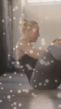 Trainer starting core set rotating med ball on mat while bokeh overlay accenting motion for fitness