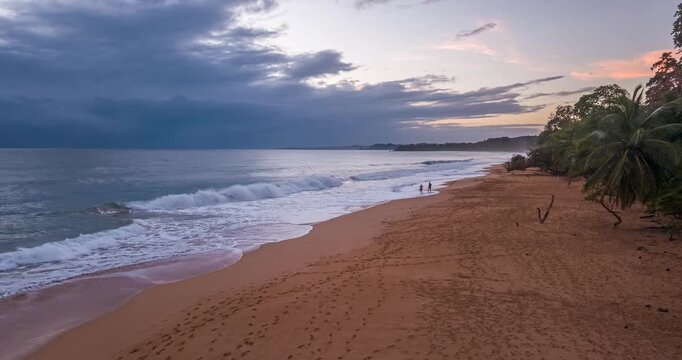 Drone flight along tropical shoreline at sunrise with waves Panama