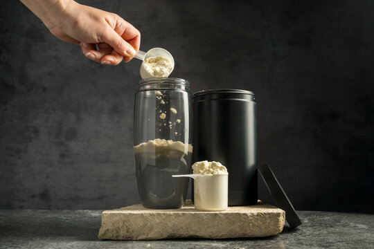 Vanilla whey protein powder and shaker, food supplements, dark background. Making protein shake drink.