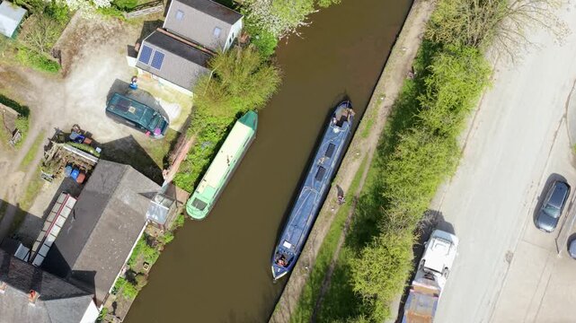 Aerial view of a traditional riverboat sailing along the water towards Barton Marina, showcasing slow travel and inland waterway tourism in the UK.