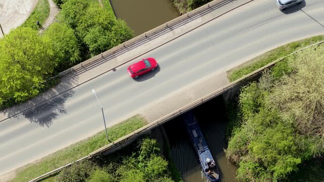 Aerial view of a traditional riverboat sailing along the water towards Barton Marina, showcasing slow travel and inland waterway tourism in the UK.
