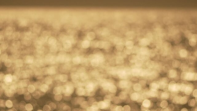 Water bokeh sunlight sparkles on the shimmering surface of the sea during golden hour creating a serene and dreamy background