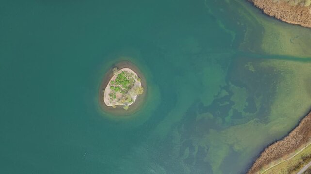 Top down aerial view of a small island on Albert Village Lake in Swadlincote, UK, featuring turquoise water