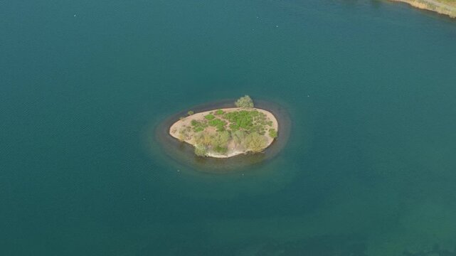 Top down aerial view of a small island on Albert Village Lake in Swadlincote, UK, featuring turquoise water