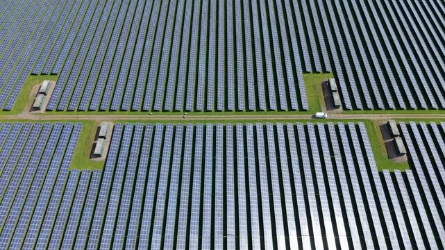 Top down aerial view of a geometric solar array and power inverter blocks, showcasing industrial symmetry and clean energy generation infrastructure in Tutbury, UK.