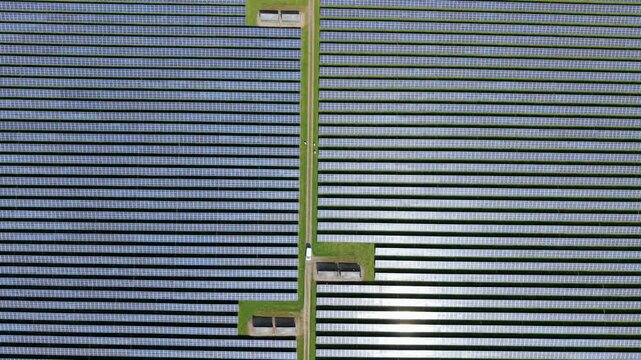 Aerial top down view of symmetrical solar panel rows on a sunny day in the UK countryside, renewable energy and sustainable power infrastructure.