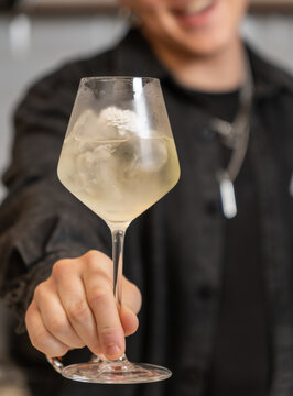 Close-up of smiling bartender holding pale floral cocktail