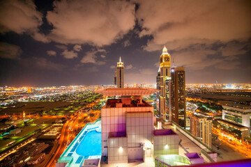Panoramic night perspective of Dubai Downtown from rooftop showing high-rise buildings, Sheikh Zayed Road lights, and vibrant urban cityscape © jovannig