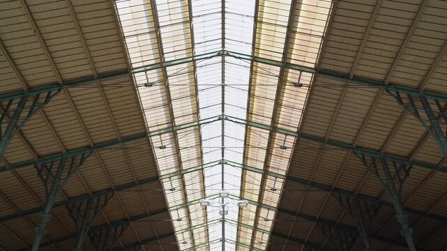 Detailed shot of the historic iron framework and glass ceiling of Gare du Nord station in Paris, France.